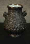 A Chinese black glaze vase with textured design, celadon glaze interior and two animal form handles.