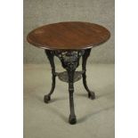 A black painted Victorian cast iron pub table with a circular pitch pine top on three curved legs