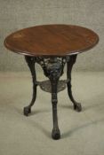 A black painted Victorian cast iron pub table with a circular pitch pine top on three curved legs