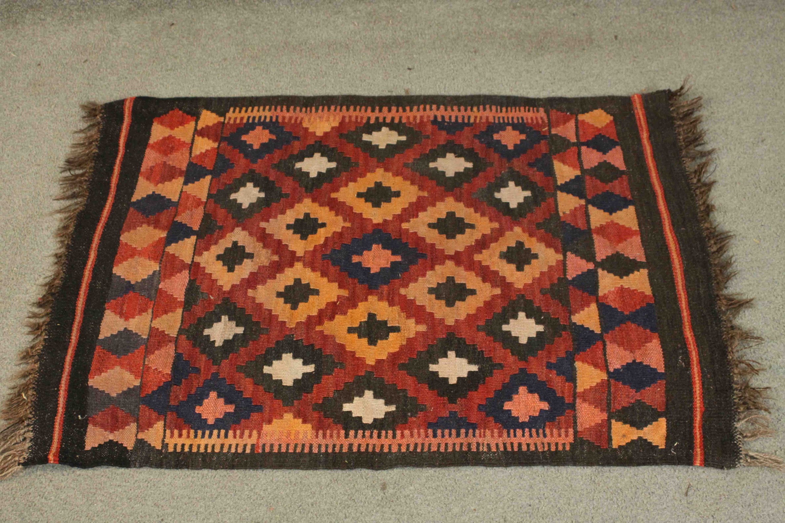 An Afghan Kelim rug with repeating diamond motif on a terracotta ground. L.94 W.69cm.