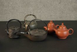 A collection of five Oriental tea pots, including two yixing clay tea pots and three cast iron