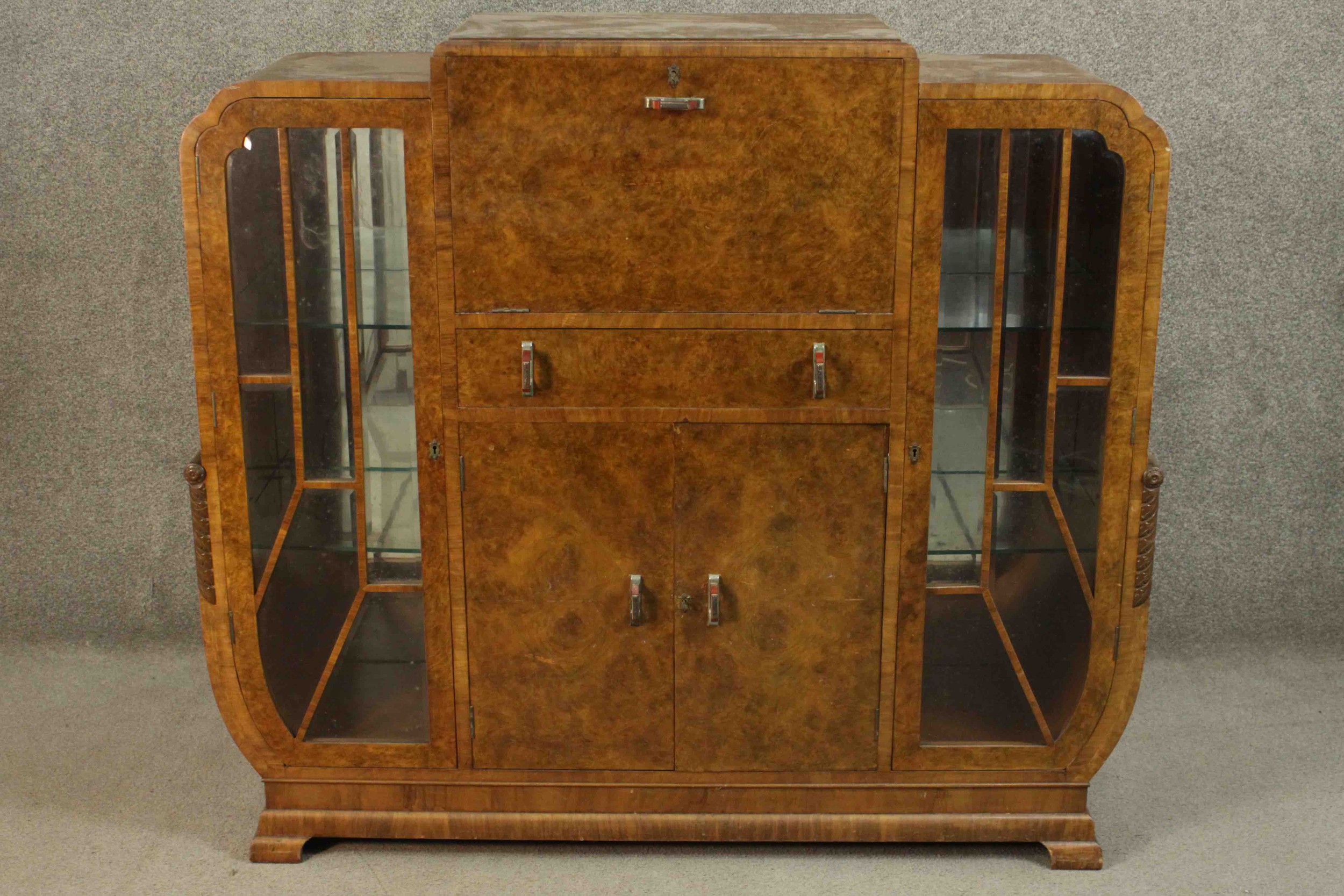 An Art Deco burr walnut cocktail cabinet with fitted and mirrored central mixing section flanked