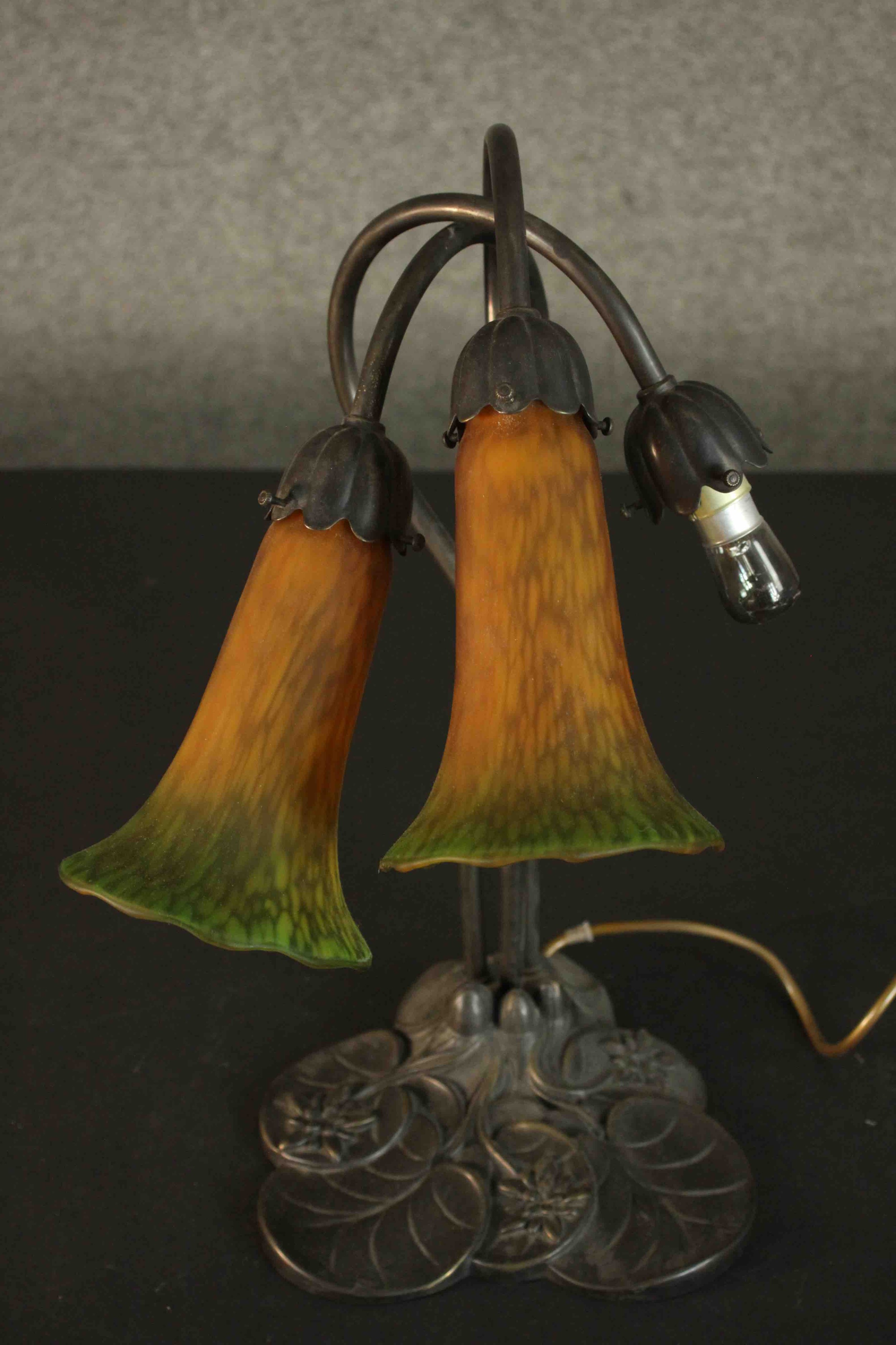 A reproduction Art Nouveau style table lamp, with two amber and green trumpet form glass shades,