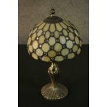 A Tiffany style table lamp, with a leaded stained glass shade on a bronzed metal base.