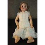 A Victorian porcelain Armand Marseille doll with glass eyes and wooden jointed limbs, stamped 390,