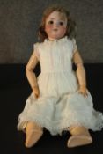 A Victorian porcelain Armand Marseille doll with glass eyes and wooden jointed limbs, stamped 390,