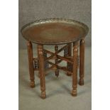 A Syrian copper tray table with carved and pierced folding base with turned centre finial. The