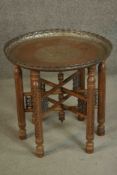 A Syrian copper tray table with carved and pierced folding base with turned centre finial. The