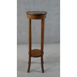 An Edwardian walnut jardiniere stand, with a circular line inlaid top over a circular undertier with