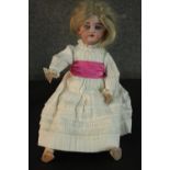 A Victorian porcelain doll with glass eyes and in a lace dress. Stamped SH 079 to the back of the