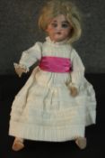 A Victorian porcelain doll with glass eyes and in a lace dress. Stamped SH 079 to the back of the