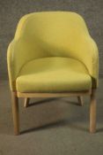 A contemporary beech tub chair, upholstered in tufted yellow fabric raised on square section