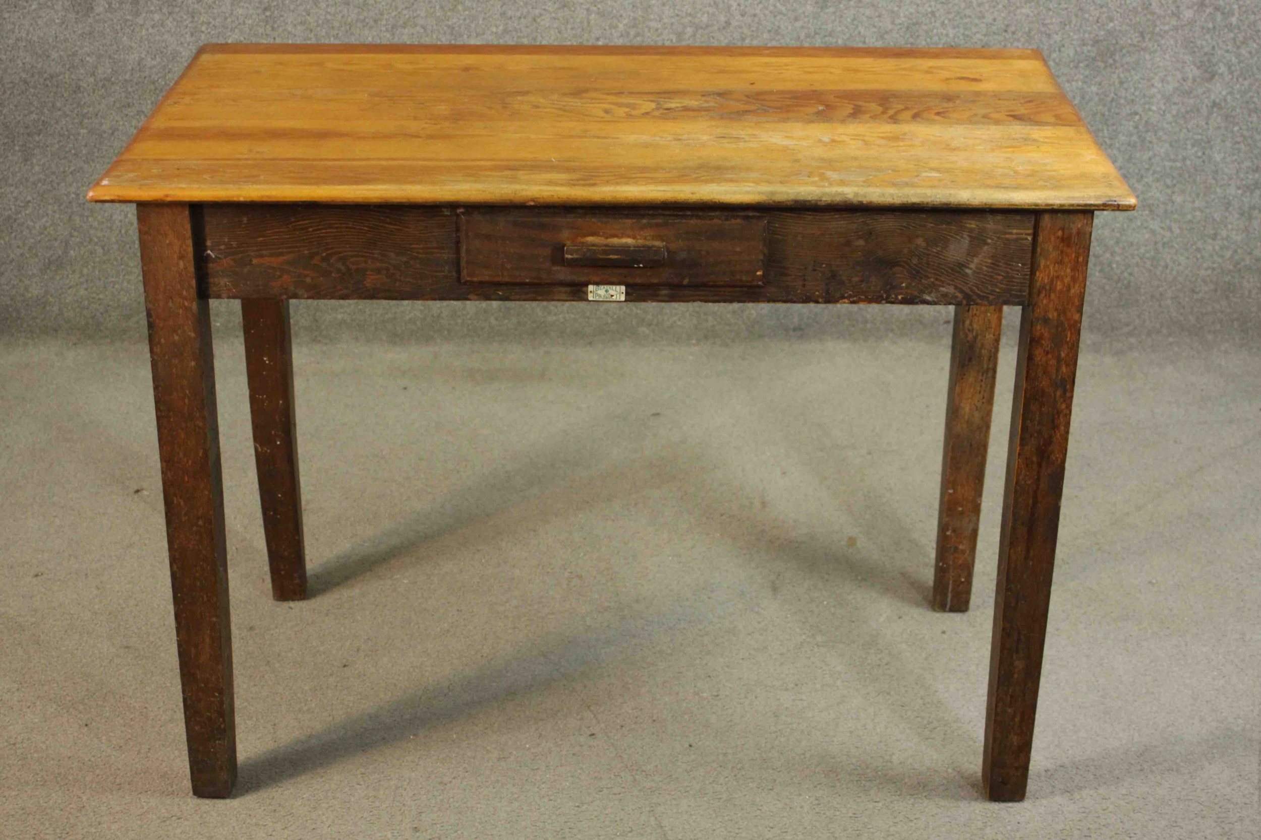 A vintage oak writing table with frieze drawer and maker's label on square supports. H.76 W105 D.