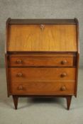 A circa 1960s teak bureau, the fall front enclosing pigeonholes above three long graduated drawers