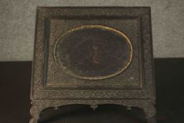 An Anglo-Indian ebonised carved easel picture frame with floral design and oval cartouche to centre.