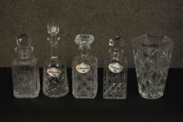 Four cut crystal decanters and a trumpeting form cut crystal vase. Three decanters with ceramic