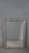 A silver painted moulded foliate and ribbon design wall mirror. H.107 W.78cm