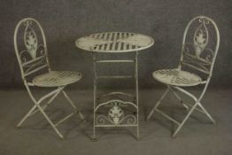 A wrought iron painted garden or bistro set, comprising a circular folding table and two chairs, the