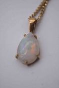 An opal drop shape pendant in five claw yellow metal setting, the opal with an approximate carat