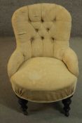 A Victorian nursing chair, upholstered in beige fabric with buttoned back and arms, on turned