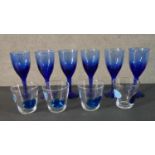 A set of six blue art glass wine glasses along with a set of four clear glasses with blue glass