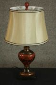 A toleware table lamp, of baluster form and painted with gilt foliate designs on a red ground,