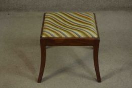 An early 19th century mahogany stool with drop in tapestry seat on sabre supports. H.38 W.42 D.42cm.