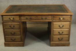 An early 20th century pedestal desk, with a leather writing insert over an arrangement of nine