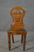 A Victorian oak hall chair, with a carved and pierced scrolling back, on turned legs.