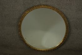 A 20th century circular gilt mirror, with a bevelled mirror plate, the frame decorated with repeated