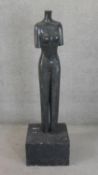 A carved dark grey marble statue of a female figure on a painted concrete block base. H.156 W.46 D.