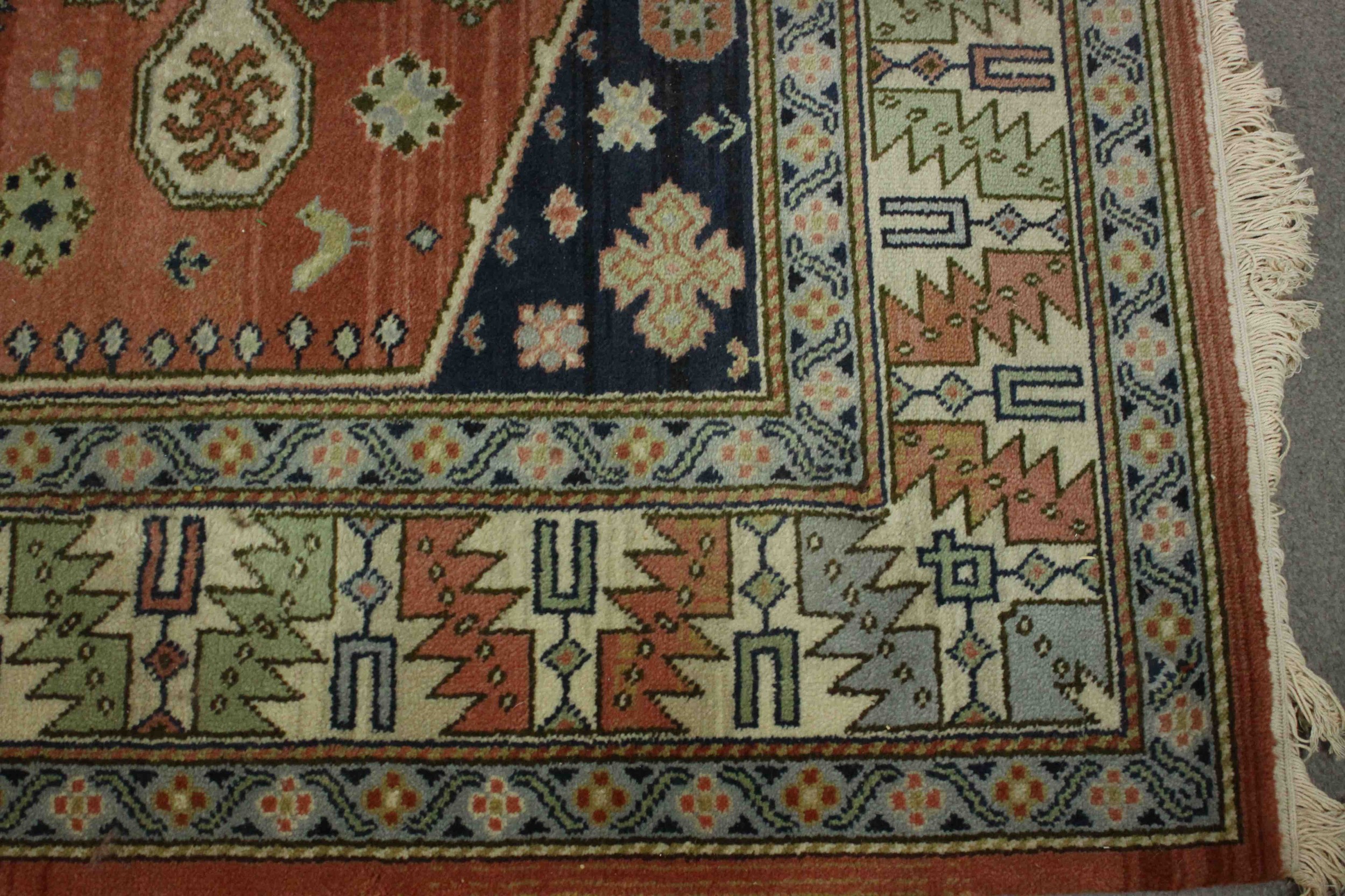 A Caucasian motif carpet with repeating stylised motifs on a terracotta field within geometric - Image 5 of 6