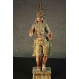 A large carved and painted 19th century Oriental statue of a deity standing on a rectangular lotus