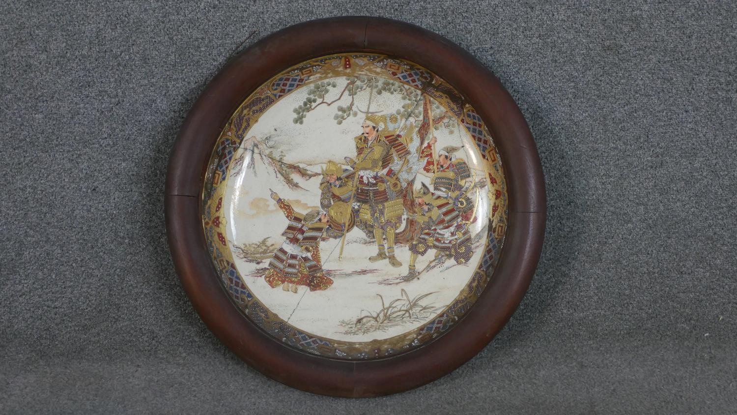 A large hardwood framed 19th century Satsuma ware charger with Japanese warriors under trees. (