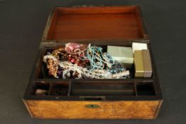 A burr walnut veneered writing box filled with a collection of costume jewellery. H.15 W.35 D.23cm.