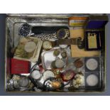 A tin of collectable items, including watches, coins (some silver), pendants, a vintage lighter