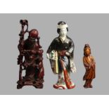 A Japanese Meiji period Arita porcelain figure and two Chinese carved hardwood figures. 24 cm