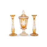 A 19TH CENTURY BOHEMIAN AMBER GLASS URN TOGETHER WITH A PAIR OF CANDLESTICKS