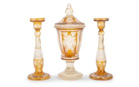 A 19TH CENTURY BOHEMIAN AMBER GLASS URN TOGETHER WITH A PAIR OF CANDLESTICKS