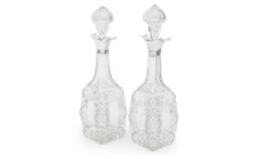 A PAIR OF EARLY 20TH CENTURY GLASS DECANTERS BY THOMAS WEBB WITH SILVER COLLARS