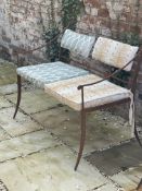 A WROUGHT IRON GARDEN SEAT WITH CUSHIONS