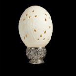 A CARVED AND PIERCED OSTRICH EGG ON SILVER PLATED STAND