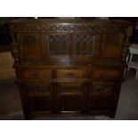 AN OAK COURT CUPBOARD WITH LINENFOLD AND PINEAPPLE DETAILING