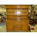 A LARGE LIGHT OAK DRESSER , HAVING A COMBINATION OF SIX DRAWERS AND TWO CUPBOARDS WITH PLATE RACK