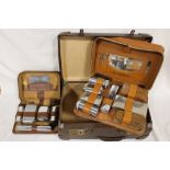 A VINTAGE SUITCASE CONTAINING TWO GENTS TRAVEL SETS