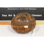 A LARGE CARVED SEED POD WITH AFRICAN ANIMAL DESIGN