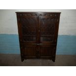 AN OAK LEADED BOOKCASE / DRINKS CABINET WITH LINENFOLD DETAIL BY JAYCEE