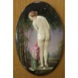AN UNFRAMED PORCELAIN OVAL PLAQUE DEPICTING A FEMALE NUDE IN A WOODLAND SETTING SIZE -19CM X 12.5CM