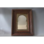 A 19TH CENTURY DECORATIVE WOODEN FRAMED MIRROR, with Islamic style arched metal mount, mirror size