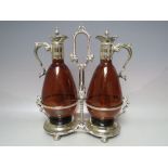 A 19TH CENTURY STYLE SILVER PLATED DECANTER STAND WITH TWO COLOURED GLASS CLARET DECANTERS,